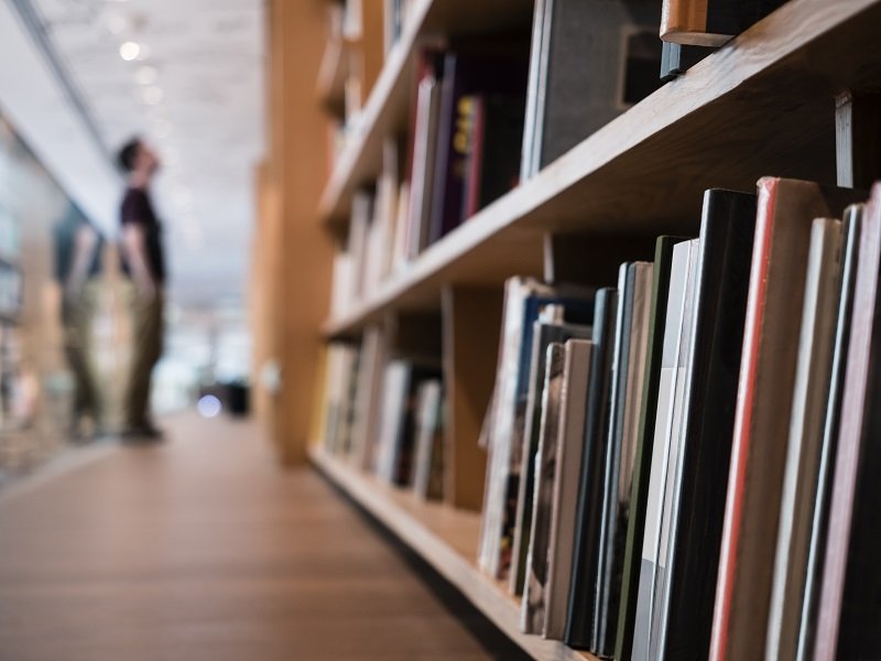 Library Cover Image - bookshelves with blurry people standing in the distance