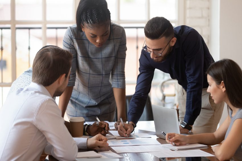 Four people in a corporate environment brainstorming while analyzing reports