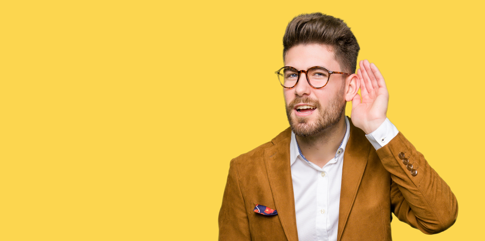 Man trying to listen closely with a yellow background