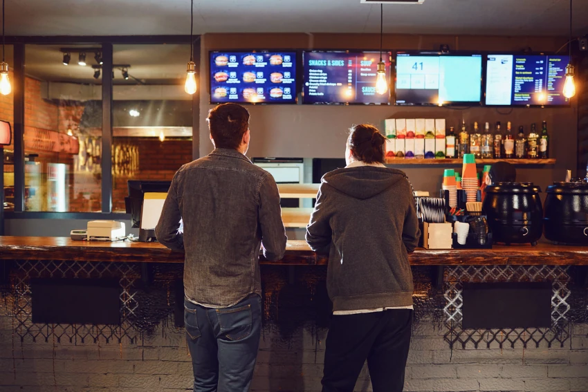 Two guys at a bar with four digital signage displays